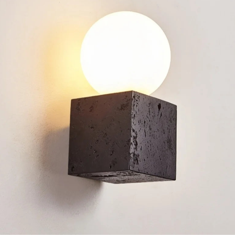 Modern wall-mounted light fixture with a concrete-like base on a plain wall.