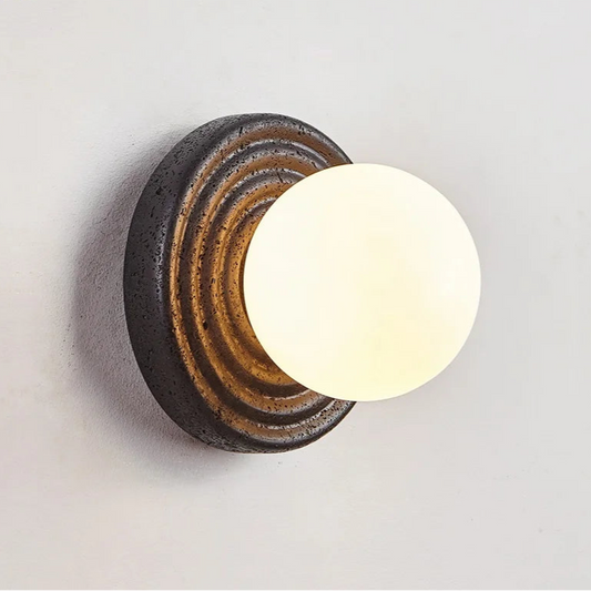Wall-mounted light fixture with a round design on a plain background
