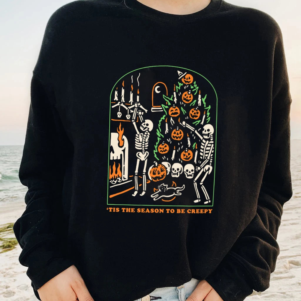Person wearing a black sweatshirt with Halloween-themed design on a beach.